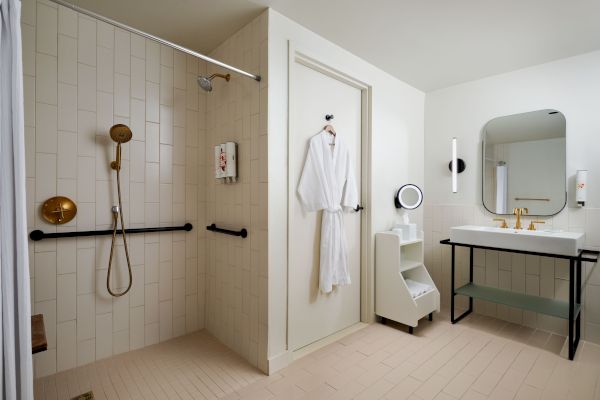 A modern bathroom with a walk-in shower, a door with a bathrobe hanging, a vanity mirror, a sink, and minimalistic decor ending the sentence.