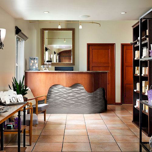 This image shows a reception area with a wooden desk, mirror, shelves of products, a table with items, and tiled flooring, in a well-lit room.