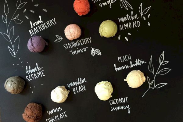 A blackboard-style menu displays various ice cream flavors: blackberry, strawberry, matcha almond, black sesame, vanilla bean, peach brown butter, coconut curry, and Swiss chocolate.