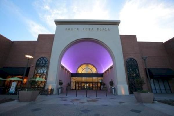 The image shows the entrance of a shopping mall with a large archway and a sign 