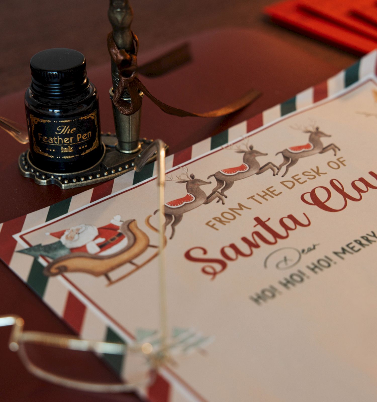 A whimsical “From the Desk of Santa Claus” letter, featuring reindeer and sleigh illustrations, an ink bottle, pen, and reading glasses.