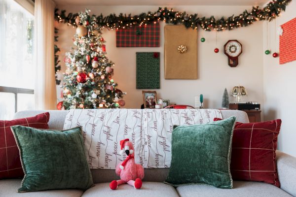 A Christmas-themed living room with a decorated tree, garlands, and festive cushions on a couch.