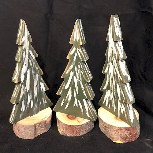 The image shows three small decorative Christmas trees with snow, each standing on a wooden base against a dark background, possibly for festive decor.