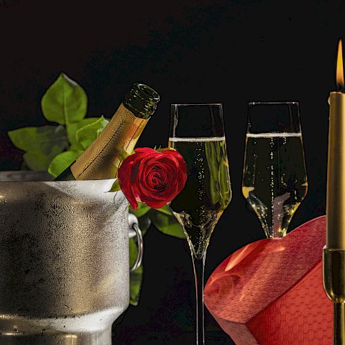 A romantic scene with champagne in an ice bucket, two filled glasses, a red rose, and a lit candle, set against a dark background.