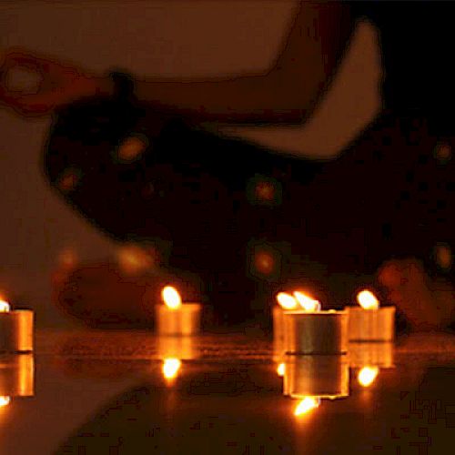 A person in a meditative pose surrounded by lit candles, creating a serene and peaceful atmosphere.