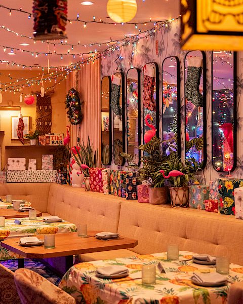 A vibrant, decorated restaurant interior with colorful lights, plants, and floral patterns, featuring tables set for dining.