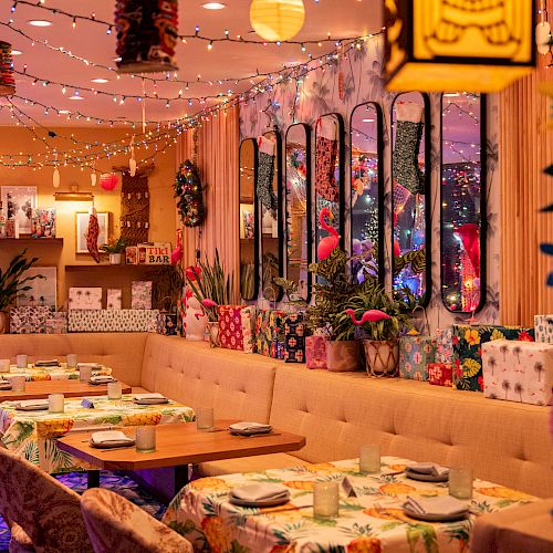 A vibrant, decorated restaurant interior with colorful lights, plants, and floral patterns, featuring tables set for dining.