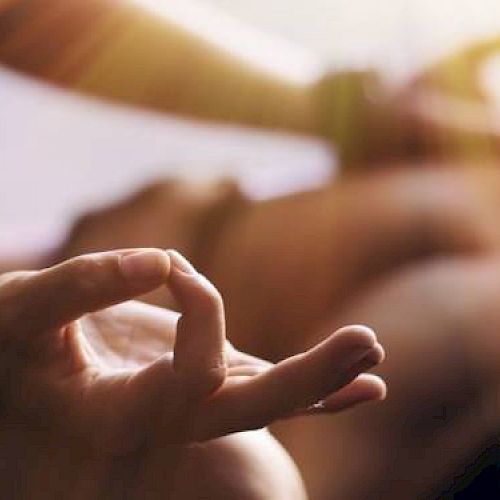 The image shows a close-up of hands in a meditation pose, with fingers forming a mudra, and sunlight streaming in.