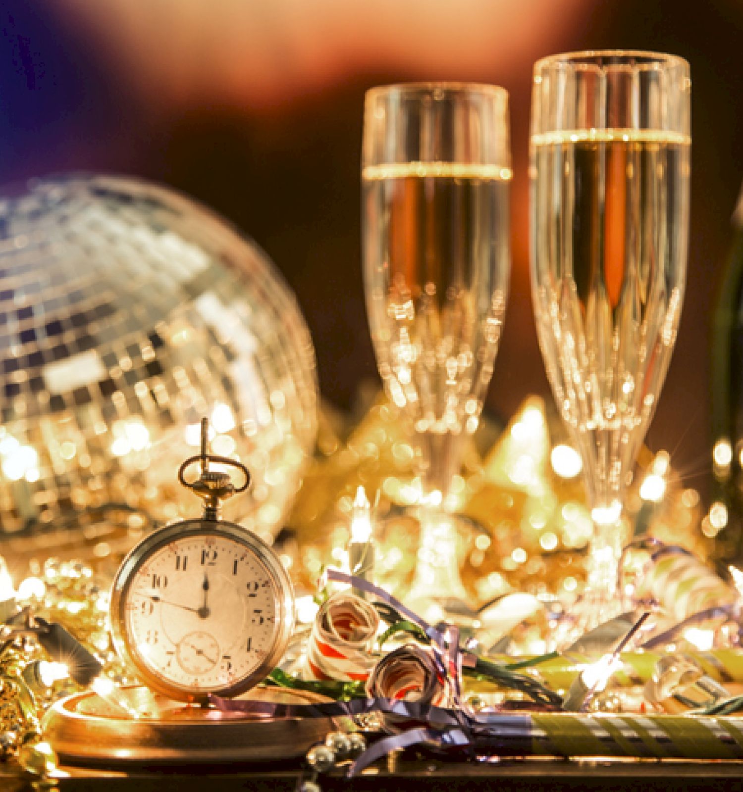 The image features champagne glasses, a bottle, a clock, a disco ball, and festive decorations, creating a celebratory atmosphere.